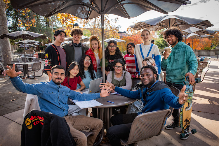 group of smiling students around outdoor table